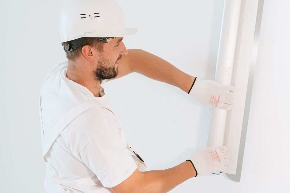 Finisher levelling a wall in white overalls